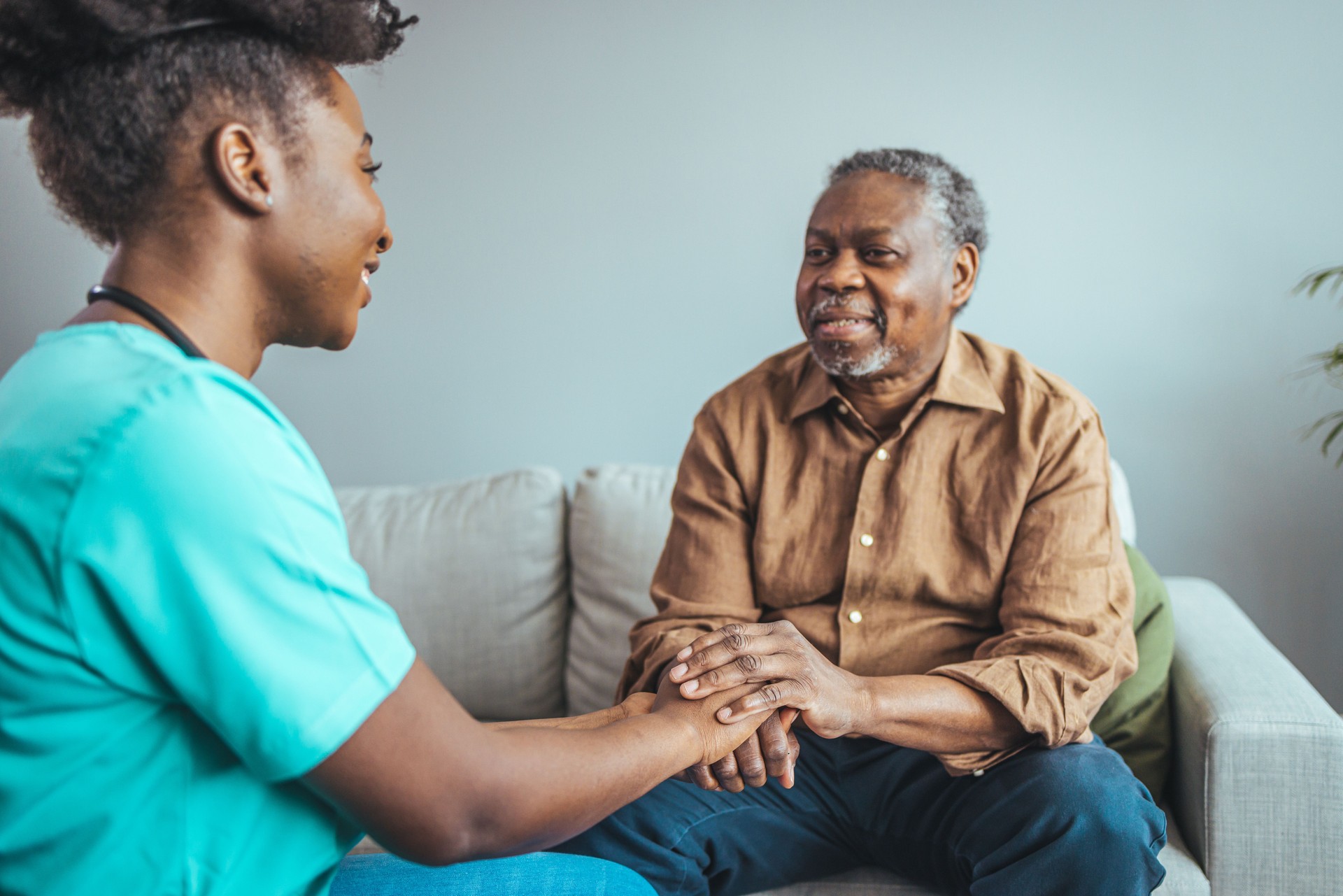 Close-up of home caregiver and senior woman holding hands.